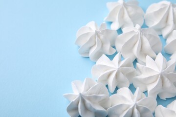 Tasty meringue cookies on light blue background, closeup. Space for text