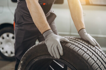 Close-up Car Mechanic holding a tire at the repair garage. Replacement of winter and summer tires © anatoliycherkas