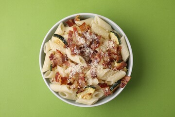 Tasty pasta with bacon and cheese on light green table, top view