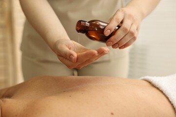 Aromatherapy. Woman receiving back massage with oil in spa salon, closeup