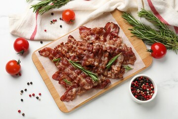 Slices of tasty fried bacon with different spices and tomatoes on light table, flat lay