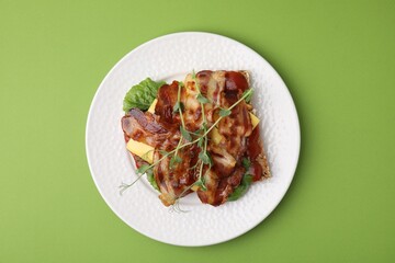 Tasty sandwich with bacon and microgreens on green table, top view