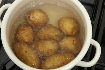 Boiling young potatoes in pot on stove, above view