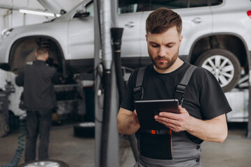 Happy mechanic using digital tablet at auto repair shop