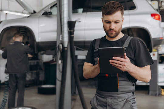 Happy mechanic using digital tablet at auto repair shop