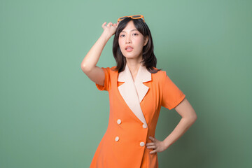 Playful woman in orange dress adjusting sunglasses