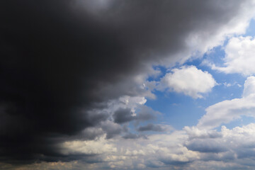 Epic Dramatic storm dark grey cumulus rain clouds against blue sky background texture, thunderstorm