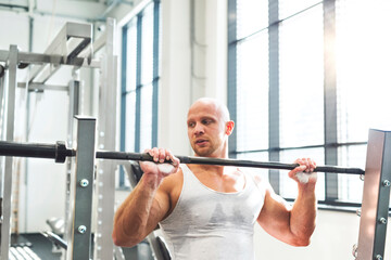 Strong man performing overhead squat pressing barbell up. Routine workout for physical and mental...