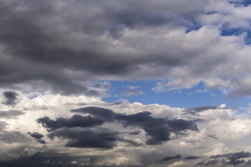 Epic Dramatic storm dark grey cumulus rain clouds against blue sky background texture, thunderstorm