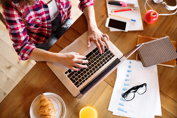 A beautiful university student is writing her thesis on a laptop, sitting at home on the couch.