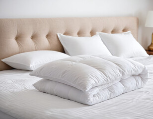 White several folded duvets lying on white bed background. Preparing for winter season, hotel or home textile