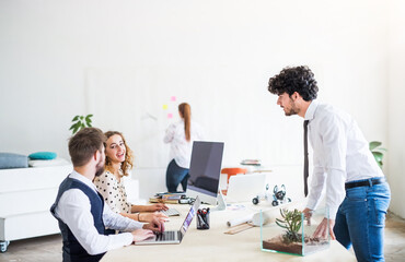 Obraz premium Young group of colleagues working on a new project together in a startup company office. Working in co-working space.