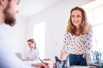 Obraz premium Young group of colleagues working on a new project together in a startup company office. Working in co-working space.