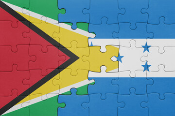 puzzle with the colourful national flag of honduras and flag of guyana .