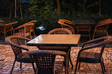 wooden tables and wicker chairs in an outdoor cafe in the evening