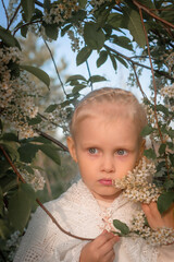 Little blonde girl in a blooming garden