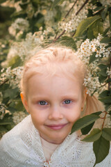 Little blonde girl in a blooming garden