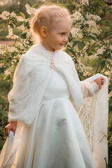 Little blonde girl in a blooming garden