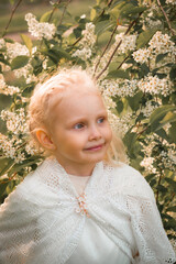 Little blonde girl in a blooming garden