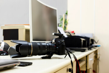 Photographer's office. Photographer's work desk has camera, computers, computer screen and printers