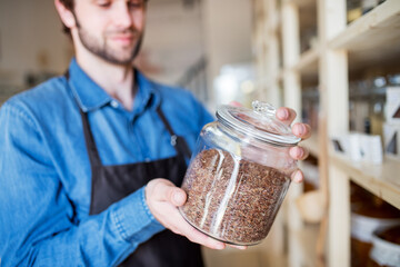 Handsome man working in package-free store using reusable containers. Zero waste shops offering...