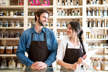 Two shop assistants in package-free store using reusable containers. Zero waste shops offering package-free bulk goods and sustainable alternatives.