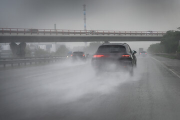 Cars driving too fast in heavy rain on wet roads with poor visibility and the risk of aquaplaning...