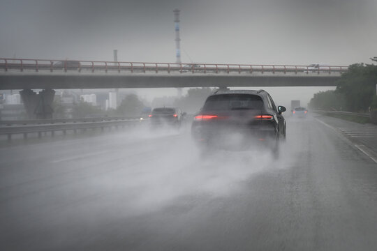 Cars driving too fast in heavy rain on wet roads with poor visibility and the risk of aquaplaning on the highway, dangerous weather for traffic and transportation, copy space, selected focus