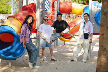Friends posing at a colorful playground, with vibrant slides in the background