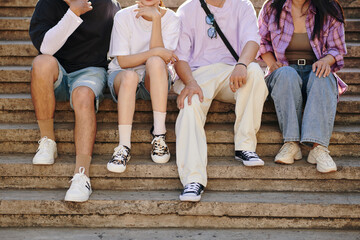 Close-up of friends feet on stairs, showing casual attire and sneakers