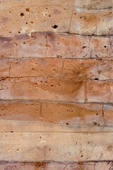 The picture shows a textured, layered surface that appears to be made of concrete or a similar material. The surface has horizontal bands of different shades, ranging from light beige to reddish-brown