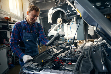 Man checking voltmeter readings in the car service center