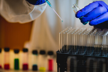 A woman scientist adding Organic reaction in test tubes in a laboratory.