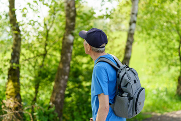 Senior man with backpack hiking in the forest. Active senior lifestyle.