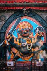Colorful statue of a fierce deity adorned with garlands in Kathmandu, Nepal. The vibrant sculpture...