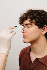 Obraz premium Process of drawing markup on male nose before rhinoplasty and septoplasty surgery. ENT doctor preparing patient for rhinoplasty surgery that changes the shape of the nose.
