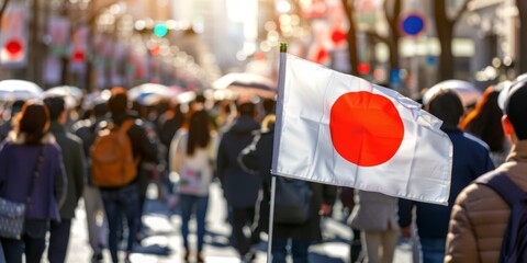 Fototapeta premium Japanese flag waving in a busy street filled with people, capturing the essence of an urban scene in Japan.