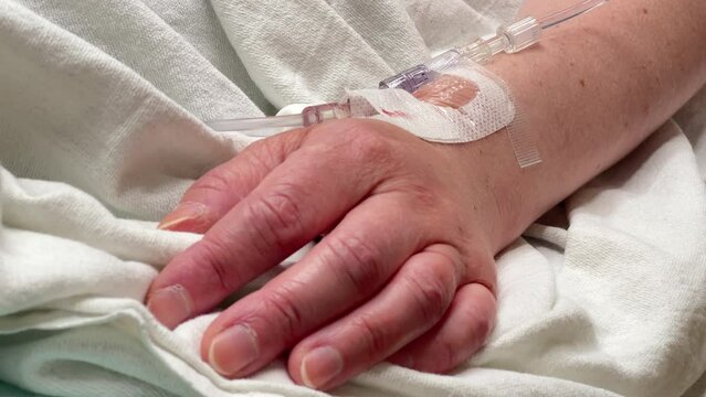 Patient laying in hospital bed with IV in wrist 4k
