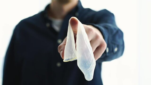 a man holds an unwrapped condom in his hands.
Method of contraception