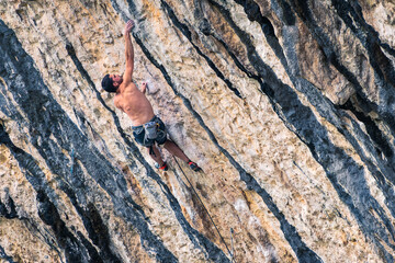 A man is climbing a rock wall with a rope