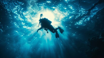 Fototapeta premium Silhouette of a scuba diver swimming underwater with sun rays streaming through the water above them, creating a stunning aquatic scene.