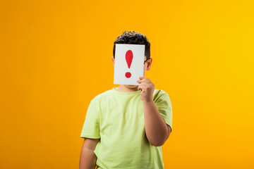 Kid boy holding exclamation point card in front of face. Education and curiosity concept
