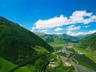 Fototapeta premium Stepantsminda tourist village of Kazbegi in the green mountains of Georgia - drone photo