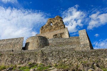 The ruins of an ancient castle against the background of blue sky and white clouds