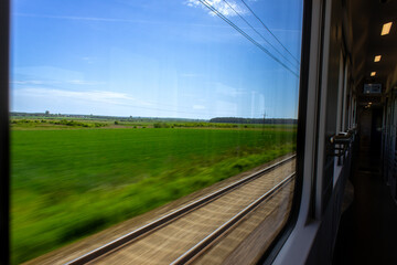 view from a moving train carriage to summer green landscape and other railroad , travel concept,...