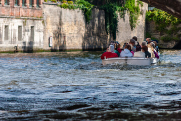 Tourists enjoying boat journey in Brugge, boat ride on historic canal, exploring the city's waterways by boat, sailing through stories of the past