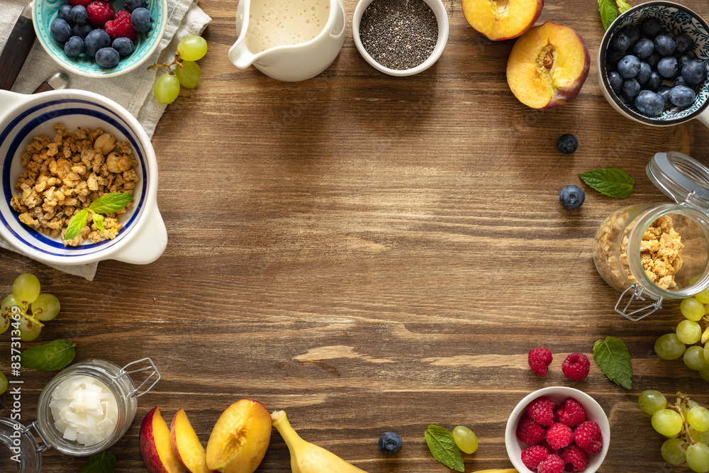Wall mural frame of a healthy breakfast preparation with granola, fresh fruits, chia seeds and yogurt on a wood - Wall murals