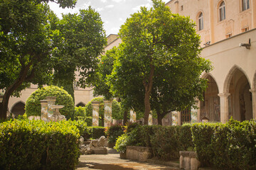 Pathway through a park with fountain and beautiful tiled pillars plated at the cloister garden of Santa Chiara Monastery, Naples, Italy. Vacation in Italy