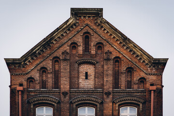 Brick facade of building with vintage decorative elements and arched windows in Krakow, Poland