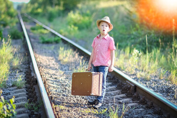 boy cowboy with suitcase waiting  and railroad